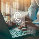 Dłonie na klawiaturze laptopa, nad nimi ikony symbolizujące prawa autorskie i ochronę własności intelektualnej. Rozważamy różnicę między parodią a pastiszem znanych postaci literackich.