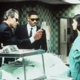 Faceci w czerni obsada: Tommy Lee Jones i Will Smith badają tajemniczy obiekt, podczas gdy Lara Flynn Boyle obserwuje.