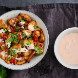 Krispiga kycklingbitar toppade med färska örter, chili och sesamfrön, serverade med en krämig bang bang sås.
