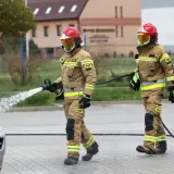 Strażak w pełnym rynsztunku PSP, z wężem wodnym, podczas akcji. Ciekawe, ile zarabia starszy aspirant w straży pożarnej za taką służbę.