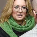 Kinga Burzyńska w zielonym szaliku i okularach rozmawia z mężczyzną.
