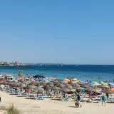 Día soleado en la playa de las Higuericas, con mucha gente disfrutando del mar y la arena bajo coloridas sombrillas.