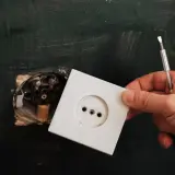 Dłoń trzyma białą ramkę gniazdka elektrycznego, gotową do montażu. To kluczowy element, który działa jak wyzwalacz wzrostowy dla domowej instalacji.