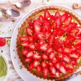 Tarte aux fraises sur pâte brisée, garnie d'une crème verte et de pistaches concassées. Un délice fruité et croquant.