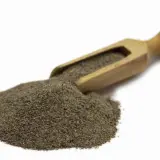 Stos mielonego pieprzu czarnego 1kg na drewnianej łyżce, gotowy do przyprawienia potraw.