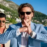 Pedro Pascal w błękitnej marynarce, z dłońmi złożonymi w geście, jakby zapowiadał kolejne z jego filmów i seriali.