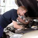 Mężczyzna pracuje przy silniku samochodu, ucząc się na kursie mechanika samochodowego dla dorosłych.