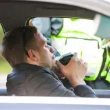 Mężczyzna dmucha w alkomat podczas kontroli drogowej. Sprawdzane są dopuszczalne promile w europie.
