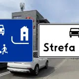 Znaki drogowe informują o wjeździe do strefy ruchu. Na niebieskim znaku widać pieszego, dziecko grające w piłkę i dom.