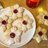 Deliziosi biscotti con marmellata a forma di fiore, spolverati di zucchero a velo, pronti per essere gustati.