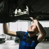 Mechanik sprawdza podwozie auta, szukając rozwiązań jak zwiększyć prześwit w samochodzie.