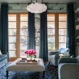 Elegant teal curtains frame French doors, showcasing a lush garden mural and reflecting current curtain trends.