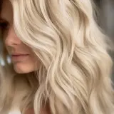 En kvinna med vackert blont hår som faller i mjuka vågor.