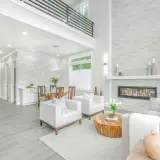 A modern living room with a fireplace, dining area, and kitchen, showcasing a full service interior design.