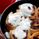 Deliciosos rollitos de canela recién horneados, cubiertos con un glaseado cremoso, listos para disfrutar.