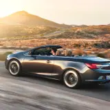 Para podróżuje kabrioletem Opel Cascada przez pustynny krajobraz o zachodzie słońca.
