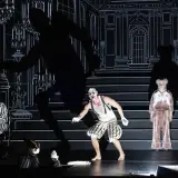 Scen från "Misantropen" på Dramaten. En clownliknande figur, en kvinna i randigt och en äldre kvinna i rosa pyjamas.