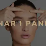 En kvinna undersöker sina finnar i pannan. Texten "FINNAR I PANNAN" syns över bilden.