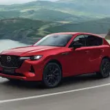 Czerwona Mazda CX-60 3.3 diesel pokonuje zakręt na malowniczej drodze.