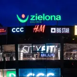 Nocny widok galerii handlowej z neonami sklepów: Zielona Galeria, CCC, H&M, Big Star, CityFit.
