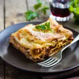 Pyszna lazania Ani gotuje się w piecu, a teraz czeka na talerzu, by ją zjeść.
