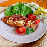 Schab po góralsku, panierowany kotlet z serem i boczkiem, podany z pomidorami i sałatą.