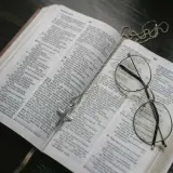 Otwarta Biblia, krzyż na łańcuszku i okulary. Może to symbolizować św. Brygidę, jej modlitwę i 12-letnie objawienia.