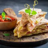 Pyszna tortilla z szynką i serem, podana z sosem pomidorowym. Idealna przekąska na szybki lunch.