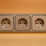 Trzy gniazdka elektryczne na drewnianym tle. Nagle nastąpiło odłączenie prądu bez powiadomienia, pozostawiając je bezużytecznymi.