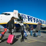 Odprawa Ryanair: pasażerowie z walizkami wchodzą po schodkach do samolotu.