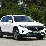 Biały Mercedes EQB na tle zieleni i nieba. Elektryczny SUV z charakterystycznym grillem i nowoczesnymi światłami.