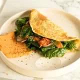Omlet z air fryera z farszem ze szpinaku, grzybów i kimchi, podany z pomarańczowym hummusem.
