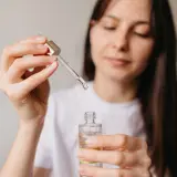 Kobieta aplikuje serum z niacynamidem, oczekując widocznych efektów poprawy kondycji skóry.