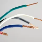 Kolorowe przewody elektryczne, każdy z odsłoniętym miedzianym rdzeniem. Różne barwy izolacji, jak zielony, biały, czarny, niebieski i różowy, sugerują ich zastosowanie jako l oznaczenie w elektryce.