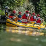 Grupa osób na żółtej tratwie podczas raftingu w Polsce. Wszyscy mają kaski i kamizelki ratunkowe, gotowi na wodną przygodę.