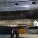 Uszkodzony skraplacz klimatyzacji objawy: zgięte żeberka, widoczne uszkodzenia mechaniczne.