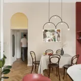 Złoty łuk nad drzwiami to stylowy sposób, by czym wykończyć łuk w salonie. Wnętrze z jadalnią i nowoczesnym oświetleniem.