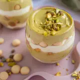 Pyszny deser w pucharku: krem pistacjowy z mascarpone, przełożony biszkoptami i posypany pistacjami.