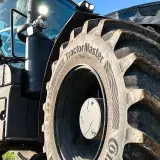 Ciągnik z masywnymi oponami, w tym jedna z napisem "TractorMaster", idealny zamiennik opon rolniczych.