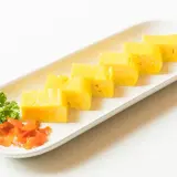 Japoński omlet tamagoyaki pokrojony w plastry, podany z natką pietruszki i marynowaną marchewką.