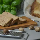 Krojony pasztet z królika, pachnący jak babciny przepis, na desce z gałką muszkatołową i świeżą bazylią.