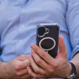 Mężczyzna w niebieskiej koszuli trzyma telefon z okrągłym wzorem. Czuć w tym nowoczesną haptykę.
