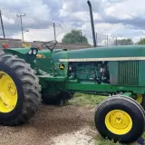 Zielony John Deere 3130 z żółtymi felgami, gotowy do pracy na polu.