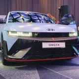 Hyundai IONIQ 5 N na prezentacji, z otwartymi drzwiami, w tle ludzie i logo Hyundai.
