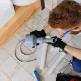 Hydraulik z przepychaczem rur przy umywalce.