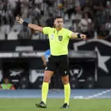 Sędzia liniowy piłka nożna w jaskrawej koszulce i żółtych getrach wskazuje kierunek gry.