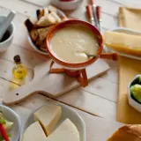 Pyszne fondue serowe z dodatkami: pieczywo, warzywa i kawałek sera. Idealny wybór, jaki ser do fondue?