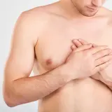 Mann hält sich die Brust, spürt ein Stechen und Verspannung.
