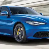 Błękitne Alfa Romeo Giulia Q4 Veloce w ruchu, z żółtymi zaciskami hamulcowymi i sportowymi felgami.