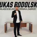Łukasz Podolski, właściciel Górnika Zabrze, w garniturze przed biurkiem. Najnowsze wiadomości z klubu.